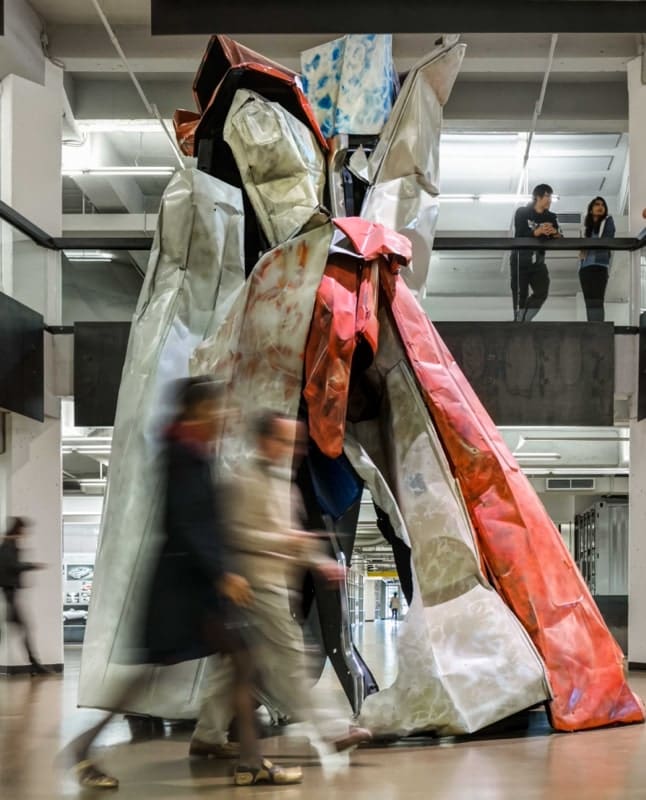 Students walking past a sculpture on campus