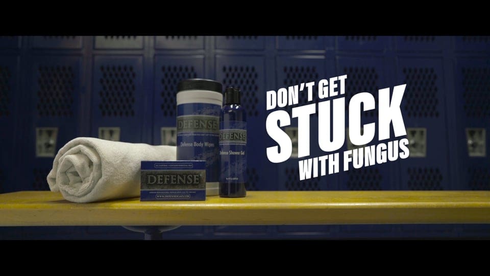 Advertisement depicting a locker room bench with a rolled up towel, and three anti-fungal creams and sprays. Bold italic white text to the right says "Don't get stuck with Fungus".