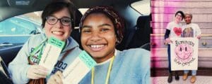 Photo photos of two girls smiling in a car and in front of a brick wall. In the car, they are holding up tickets. In front of the wall, they are holding up a poster with a pink smiley face and curly text that says :feminism is for Everyone"