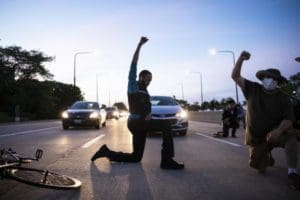 kneeling man holding his fist up to the sky