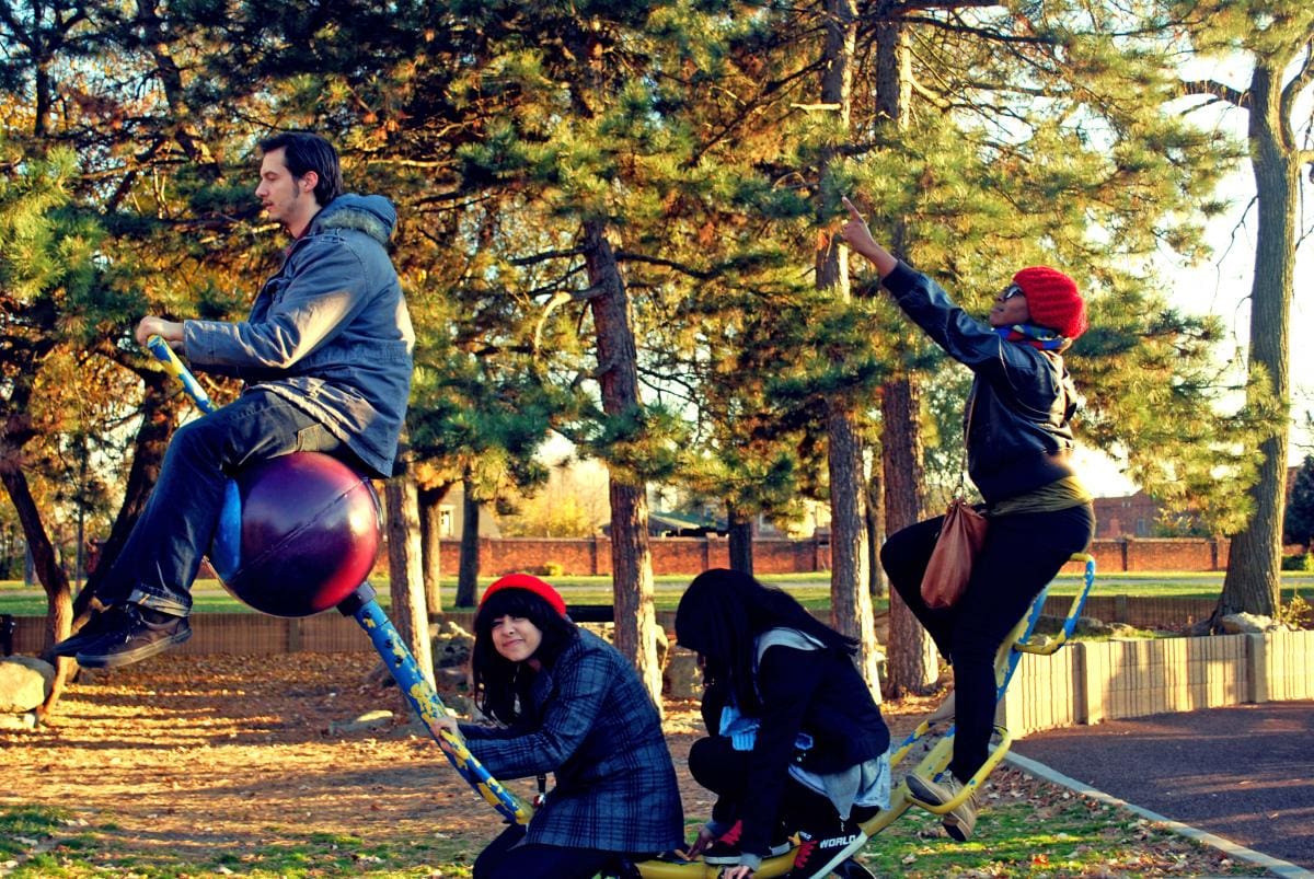 Four CCS Students sitting on an interactive sculpture in a park during the autumn.