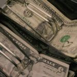 Close up photo of dollar bills stacked inside the money slot of a cash register.