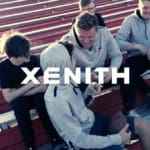 Photo of five young boys in black shirts and grey hoodies sitting together on some outdoor bleachers. On top is bold white text that says "Xenith".