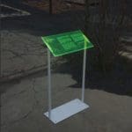 Photo of an information placard in a parking lot. The stand is grey metal, and the placard is semi-transparent and neon green.