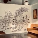 Photo of a black and white mural of flowers painted on a wall in a living room.