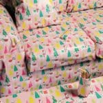 Photo of a couch and living-room coffee table completely wrapped in pink Christmas wrapping paper with green pine trees and white llamas.