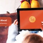 Overhead shot of a child on a tablet displaying a golden token with a train on an orange background. White text in an orange textbox says "Full steam ahead. A well rounded learning experience"