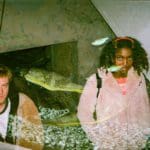 Photo of two people touring Belle Isle. A reflection of fish in an aquarium tank is imposed on top of the photo.