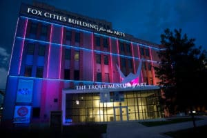 Front of the TroutMuseum of Art at night lit up with blue and pink lights 