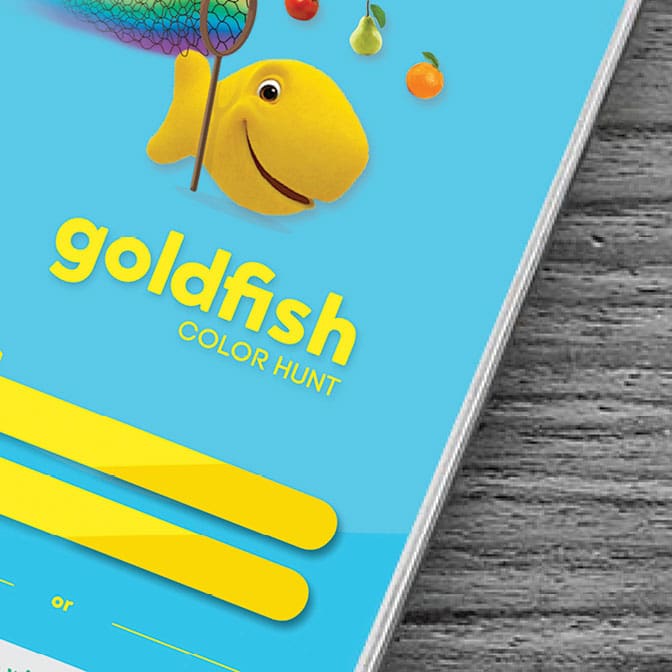 Close up of an advertisement that has a yellow cartoon goldfish holding a rainbow net above yellow text that says "Goldsfidh Color Hunt". All is on a blue background.