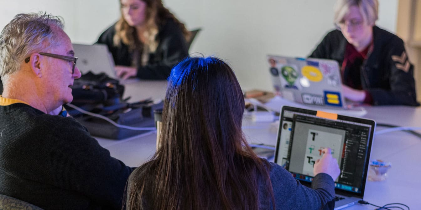 Photo of four people working on laptops together