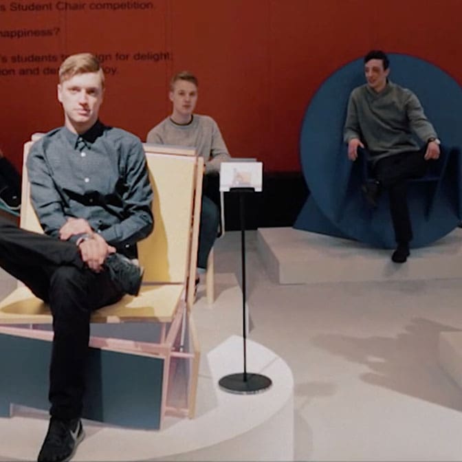 Photo of three men sitting in abstract furniture in an exhibition