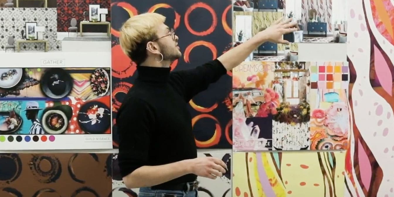 Photo of someone presenting and speaking about art hung up on a wall