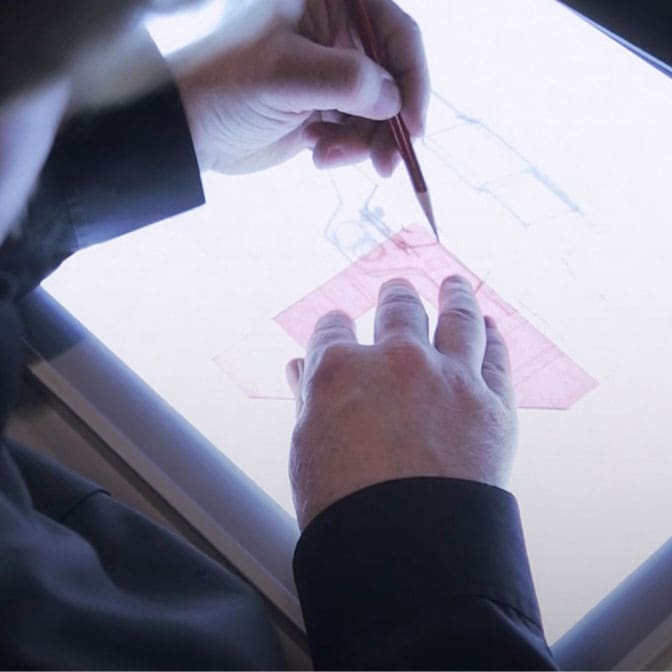 Cllseup photo of two hands working on top of a light box.