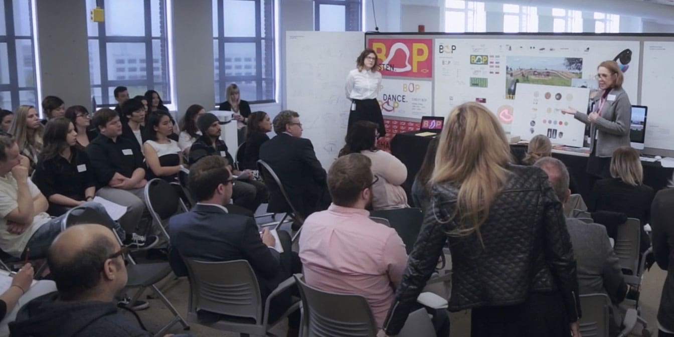 Photo of a woman giving a presentation to an audience.