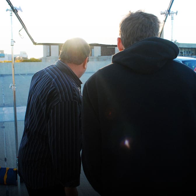 Picture of two men with their backs to the camera, looking at a building in the distance