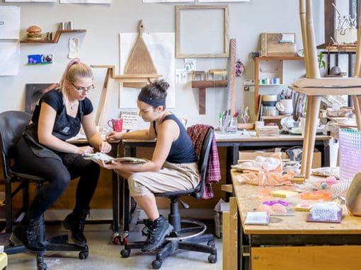 One woman teaching another in an art studio.