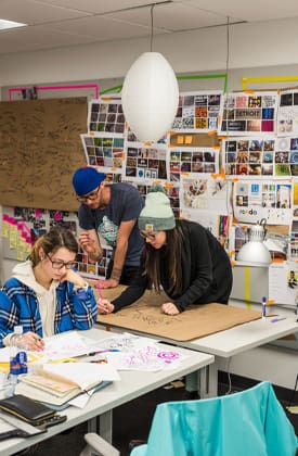 students working around a table with work hanging on the walls
