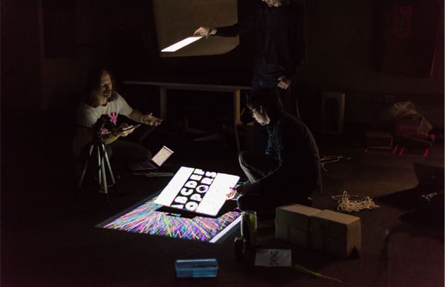 student in a dark room photographing a book