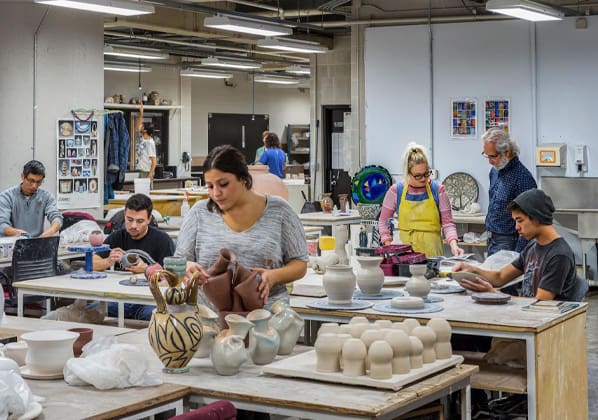 students painting ceramics at a worktable