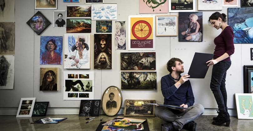 A student studying by a wall full of illustration designs
