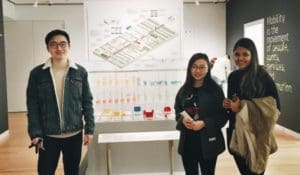 students standing in a museum in front of their transportation design work