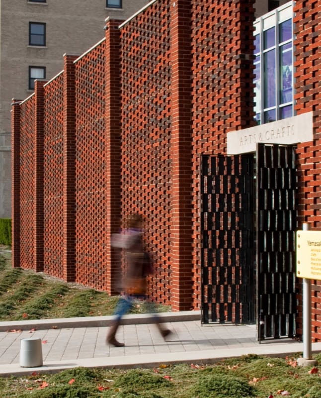 A student walking into the arts and crafts building on campus