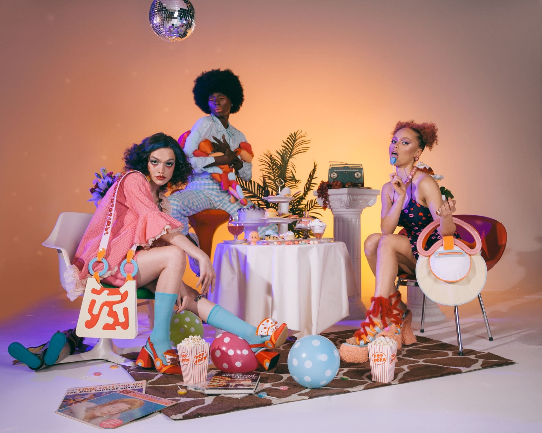 A still photograph of fashion models posed around an abstract dinner table setting