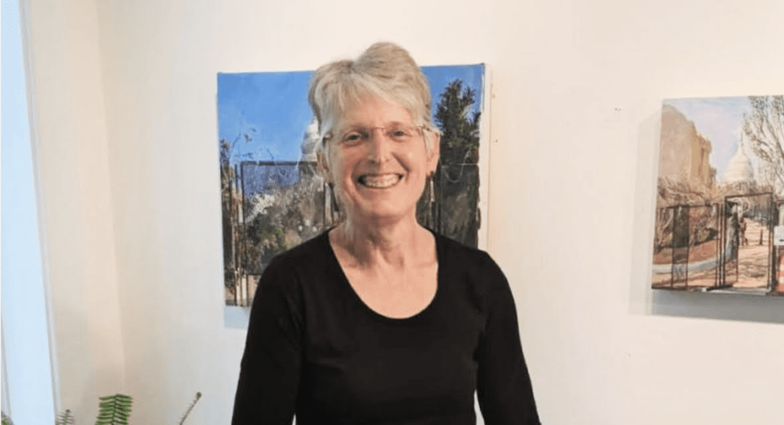Headshot of painter Elaine S Wilson in front of two of her pieces.
