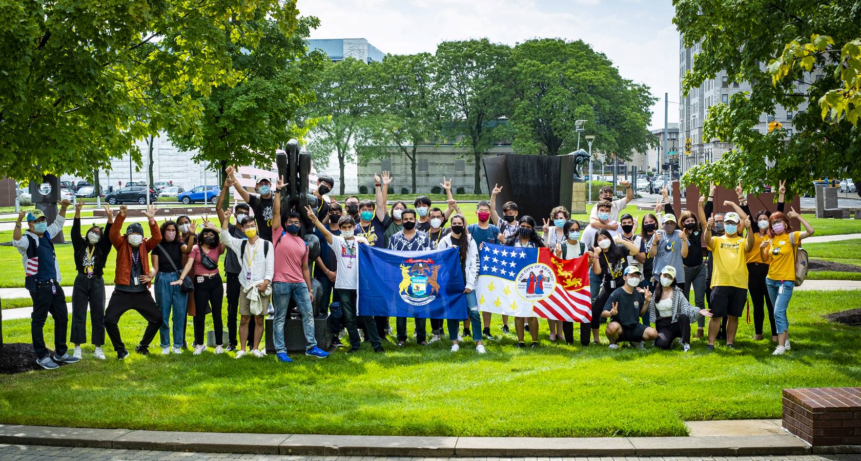 hero photograph of a diverse group of students holding a city of Detroit flag.