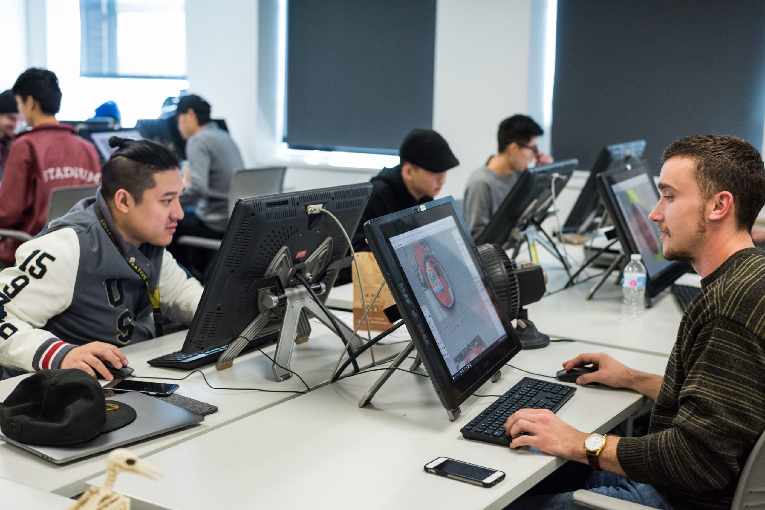students working at an open work desk with computers in a Transportation Design lab