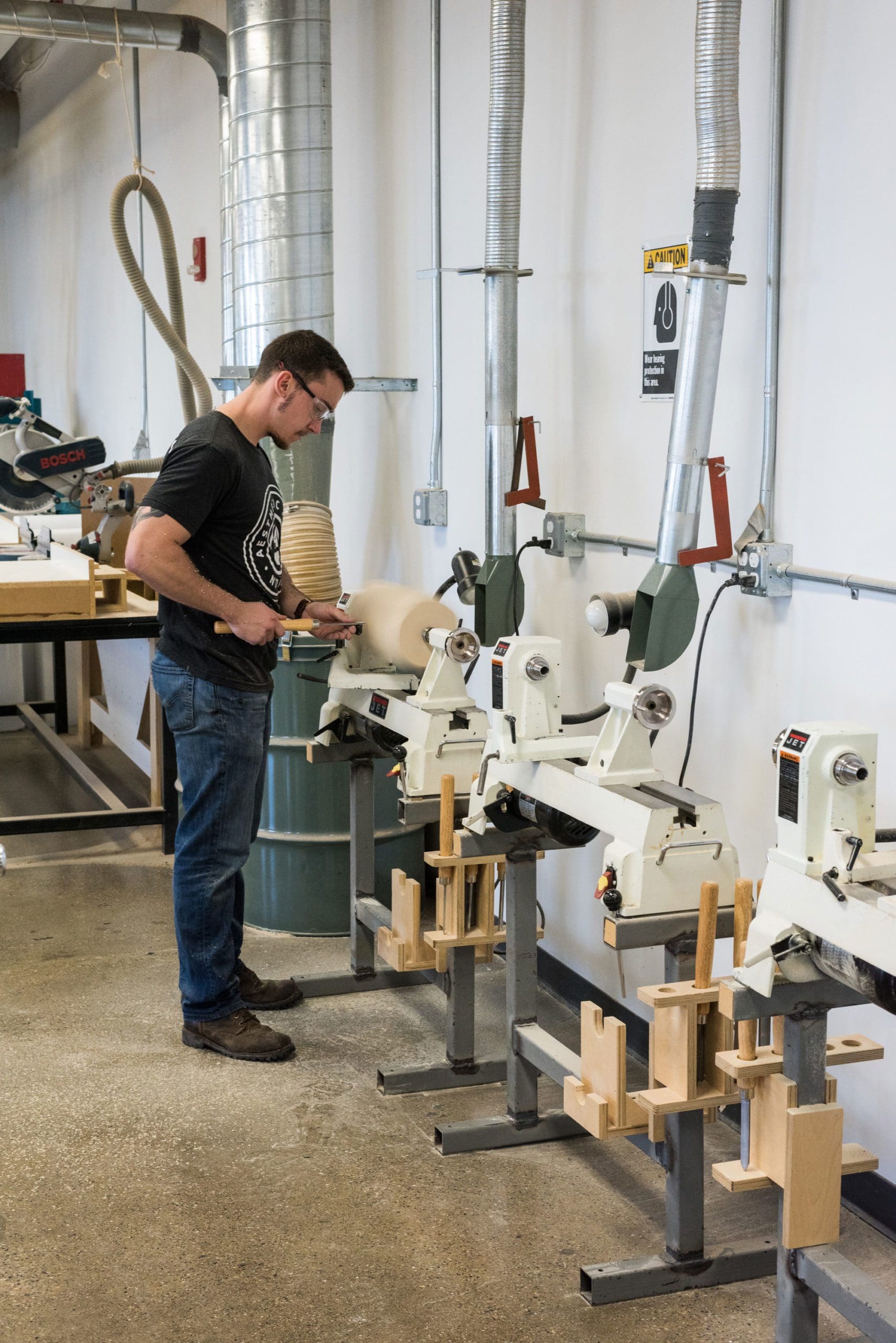 An image of a student using a lathe in a wood workshop for a Transportation Design class