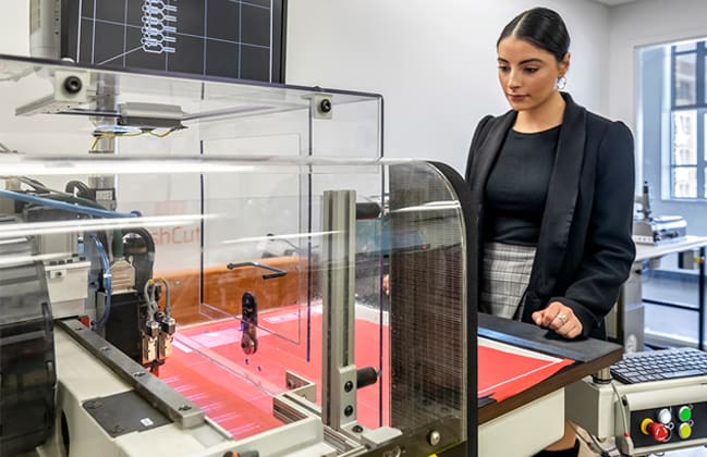 A photograph of a student using a 3D printer