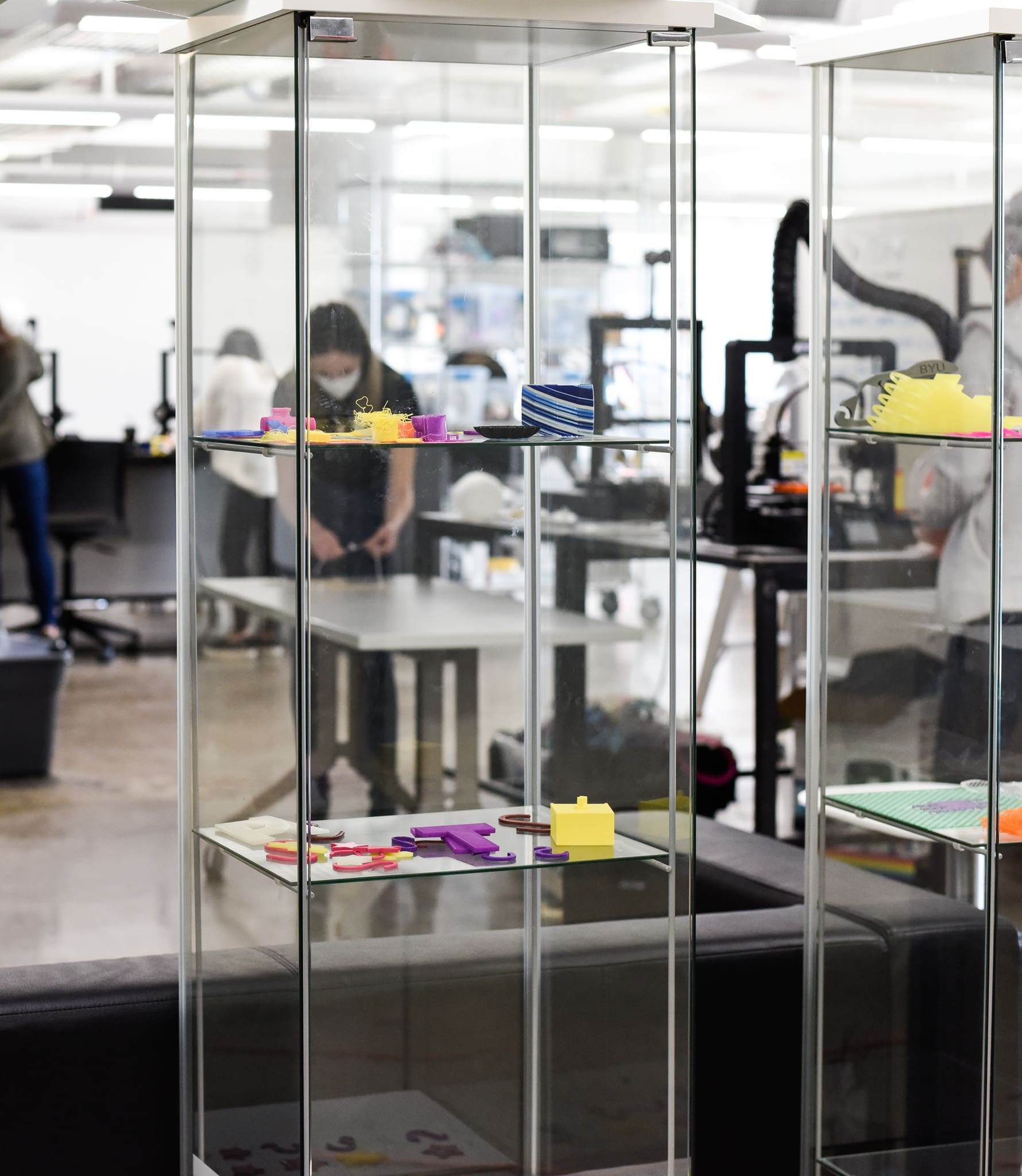 glass cases with brightly colored materials and a student working at a table behind them