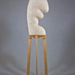 artwork of Ebitenyefa Baralaye. White ceramic sculpture comprised of organically shaped stacked ovoids balanced on wooden stilts.