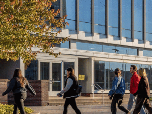 students walking on campus in the fall in front a glass building