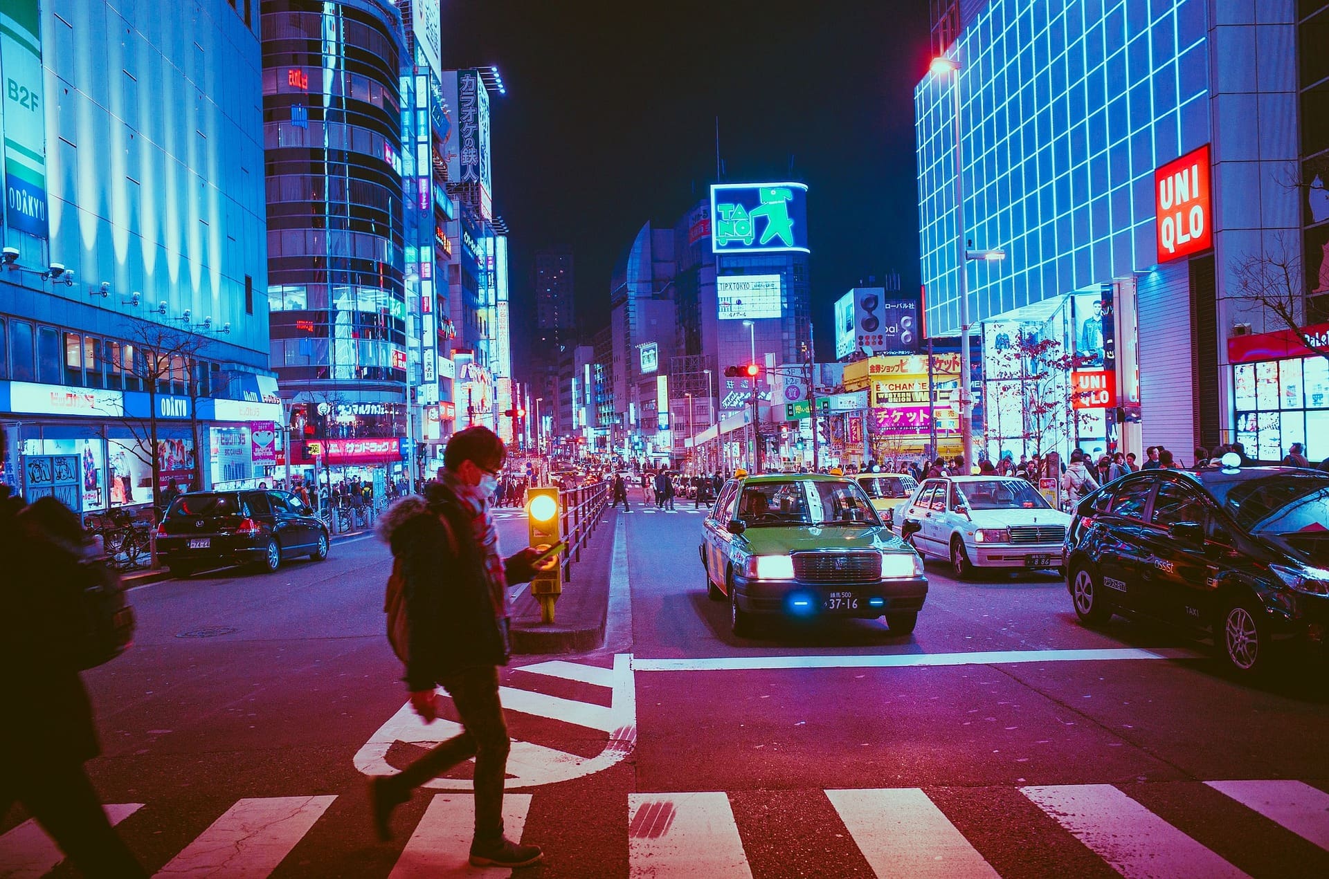 pedestrian walking in Osaka Japan after dark illuminated by pink street lights