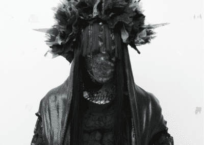 person dressed in black lace with lace and black bangs covering face and crystal horns coming from head