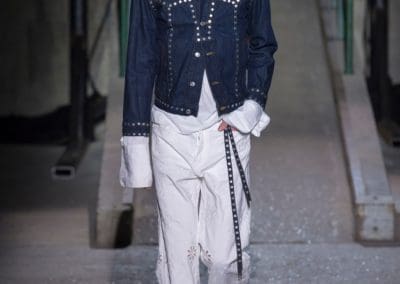 model with jean jacket and silver buttons, white shirt and white pants with cut outs