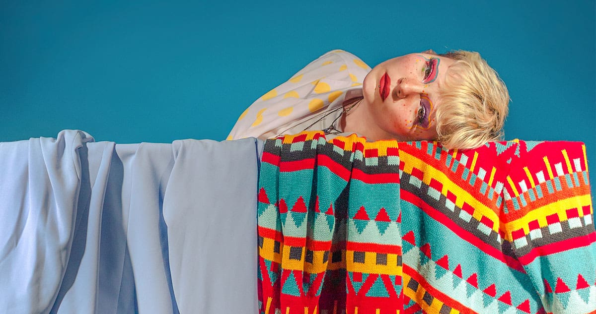 Photography of a model laying horizontally on a patterned blanket