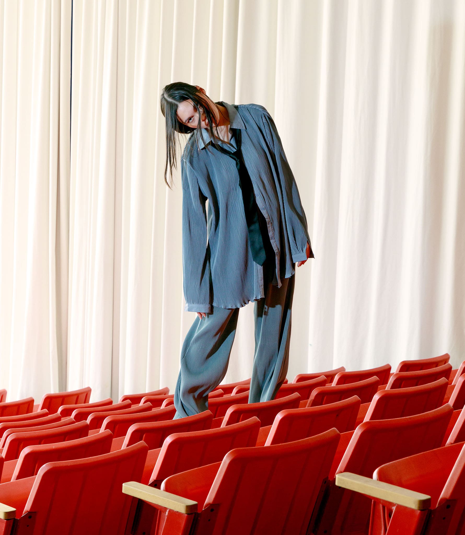 Photography of a model standing in a movie theater in a denim outfit