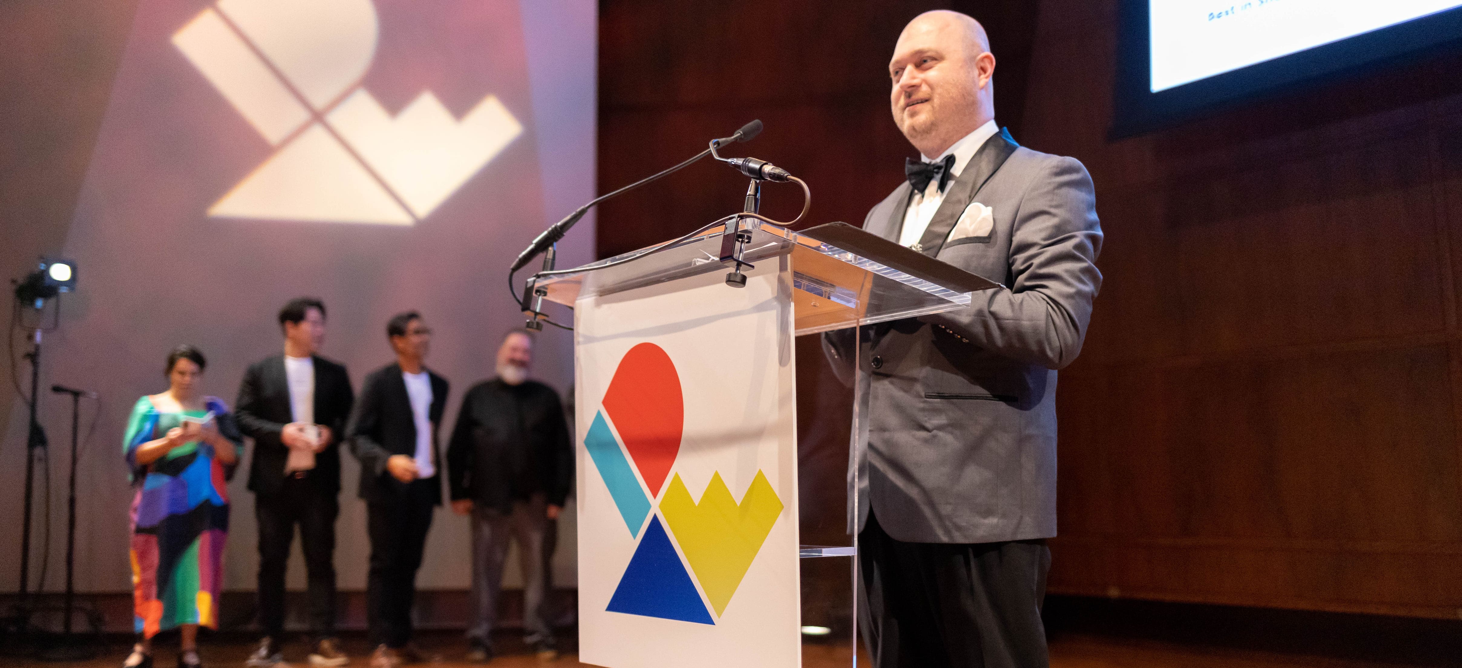 a presenter speaking at a podium for the IDEA awards