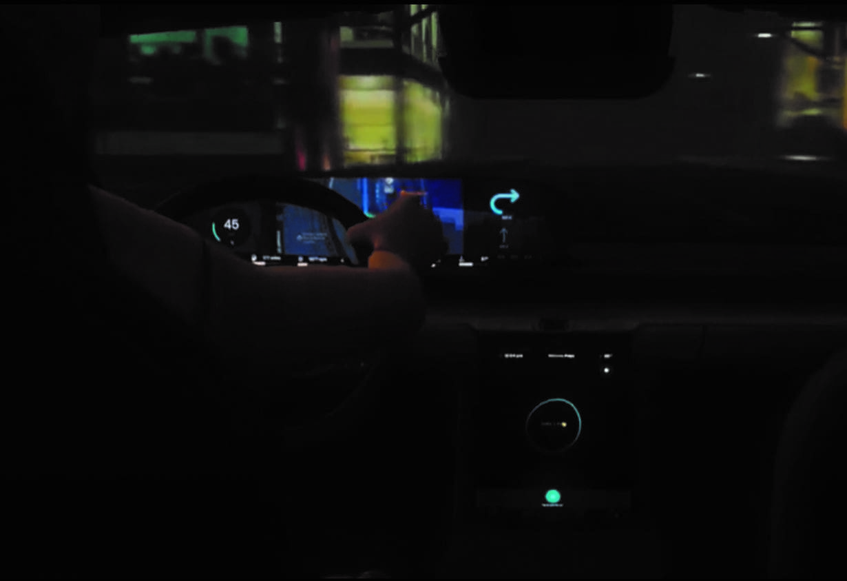 interior of a car at night with an arm and hand holding the steering wheel