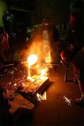 molten iron being poured into molds in a dark room