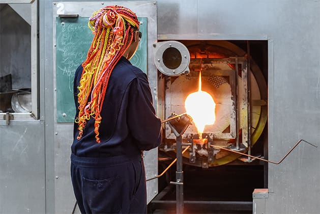A student fires glass in a glory hole oven in the glass studio