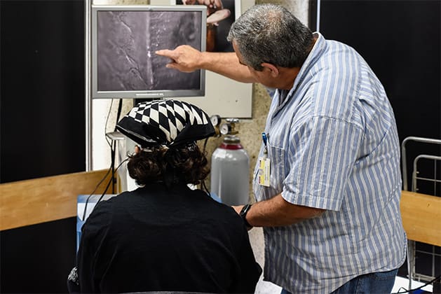 A faculty member points out details on a monitor in the jewelry making studio