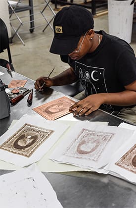 A student transfers images from a mold to paper in the printmaking studio
