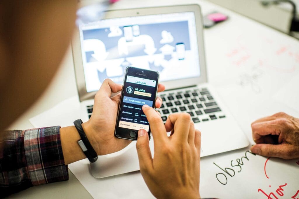 Student testing an app on their phone near their laptop