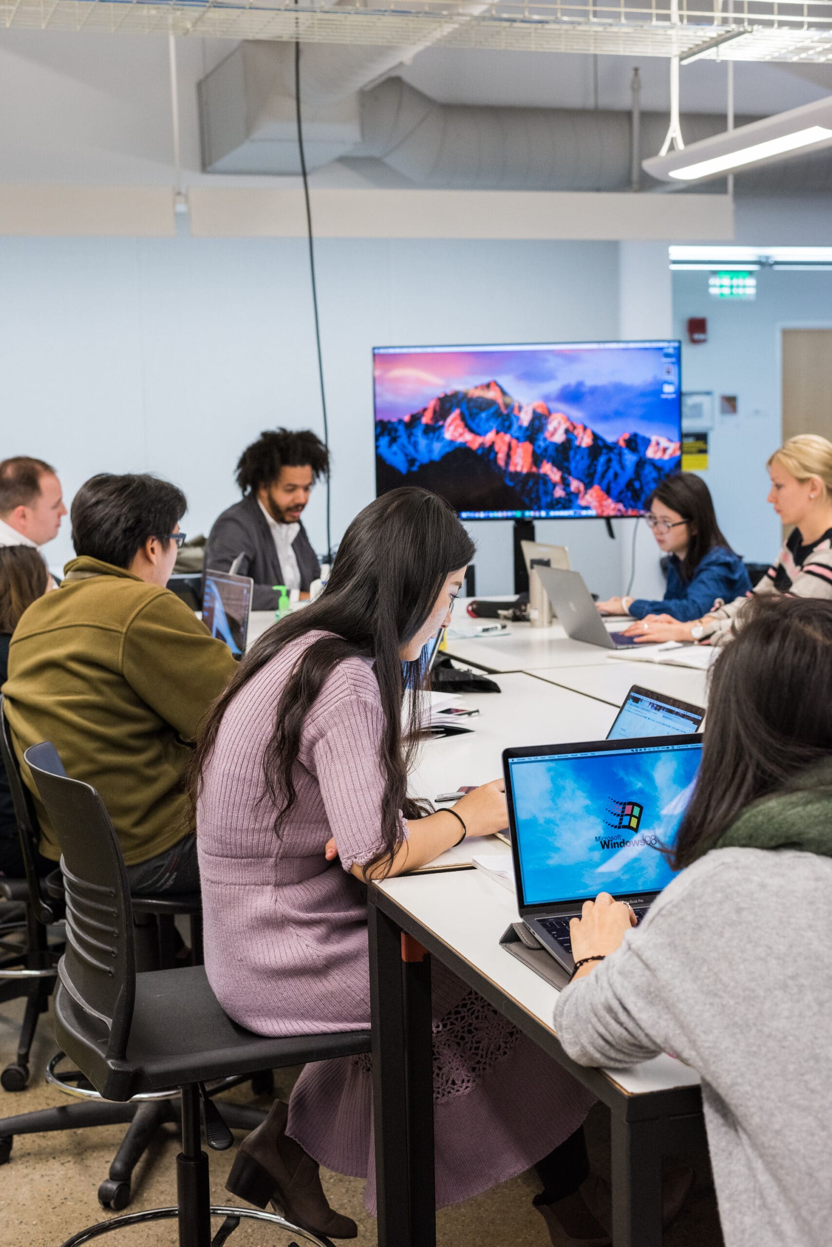 A group of students working on laptops around a table