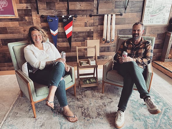 Rachel and Sam Conant sitting in front of a wall with wooden panel